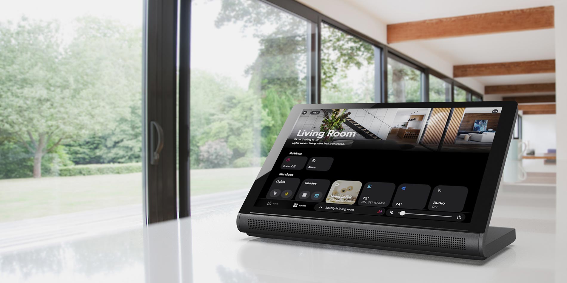 Smart home automation control tablet resting on a counter with floor-to-ceiling windows behind